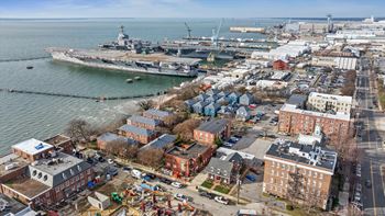 A large ship is docked at a port with several buildings in the foreground.