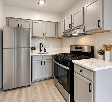 Baltimore apartment for rent - A modern kitchen with a stainless steel refrigerator, black stove, and white countertops.