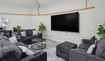 A living room with grey couches and a black television.