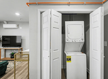 A white tankless water heater in a room with a television and a plant.