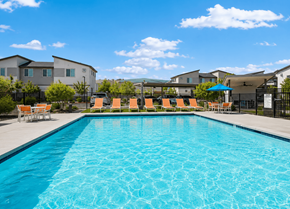 Phoenix apartment for rent - A swimming pool with orange chairs and a blue umbrella in front of a residential area.