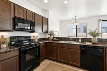 Tucson apartment for rent - A kitchen with dark wood cabinets and black appliances.