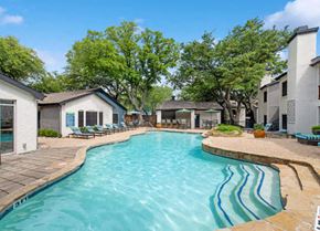 Dallas apartment for rent - a large swimming pool with buildings and trees in the background at Heatherstone, Texas