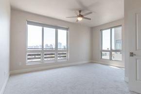 San Diego apartment for rent - A spacious room with a ceiling fan and large windows overlooking a cityscape.