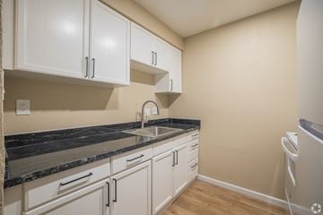 Antioch apartment for rent - A kitchen with white cabinets and a black countertop.