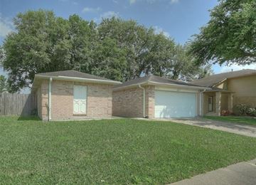 Pearland apartment for rent - a small brick house with a blue garage door
