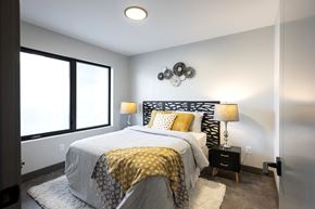 Calgary apartment for rent - A bedroom with a bed, two lamps, and a wall hanging.