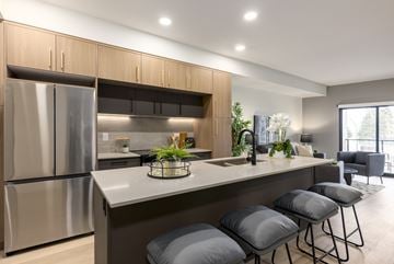 Calgary apartment for rent - A modern kitchen with a stainless steel refrigerator and grey bar stools.