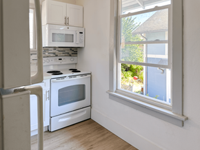 Seattle triplex for rent - A white kitchen with a window overlooking a house.