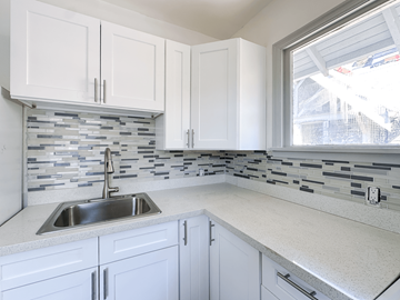 Seattle triplex for rent - A kitchen with white cabinets and a silver sink.