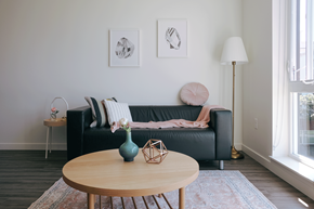 Seattle apartment for rent - A living room with a black couch, a wooden table, and two framed pictures on the wall.