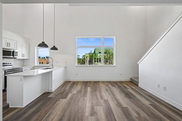 Denver apartment for rent - A kitchen with white cabinets and a window overlooking a green landscape.