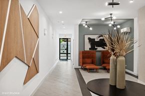 Chicago apartment for rent - A modern interior with a wooden panelled wall and a black table with a vase on it.