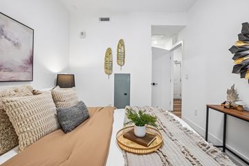 Denver apartment for rent - A living room with a brown sofa and a wooden tray with a plant and a book on it.