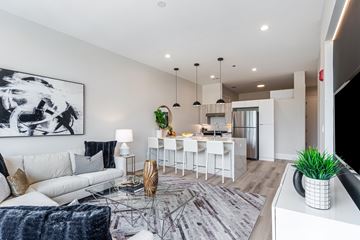 Chicago apartment for rent - A modern living room with a white sofa, a glass coffee table, and a large abstract painting on the wall.