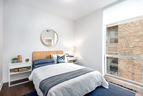 Chicago apartment for rent - A bedroom with a bed, nightstand, and a round mirror on the wall.