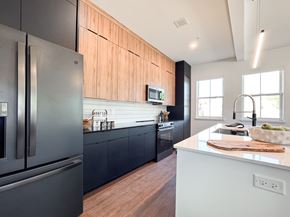 Pittsford apartment for rent - A modern kitchen with a black refrigerator and wooden cabinets.