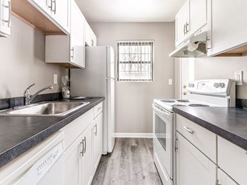 Well-equipped kitchen with white cabinetry, faux marble countertops, electric stove, refrigerator, and dishwasher