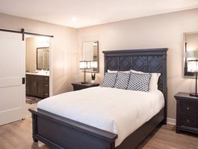 Victor townhouse for rent - Interior of Champion Reserve Townhome primary bedroom with ensuite bathroom and faux wood flooring.