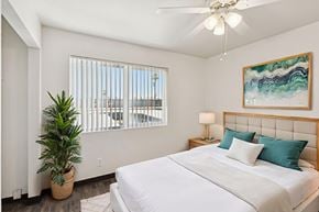 Phoenix apartment for rent - A bedroom with a large bed, a ceiling fan, and a plant.