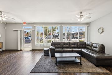 Phoenix apartment for rent - A black leather couch sits in a living room with a ceiling fan and a large window.