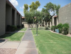 Phoenix apartment for rent - a sidewalk in front of a building with grass and trees