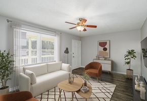 Gastonia apartment for rent - A living room with a white couch, a brown chair, a coffee table, and a ceiling fan.