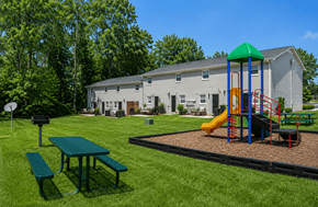 Gastonia apartment for rent - A playground with a green slide and a picnic table in front of a grey building.