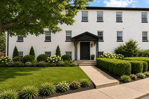 Durham apartment for rent - A white building with a black door and windows surrounded by greenery.