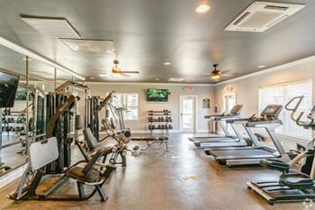 A spacious fitness room with cardio equipment and a flat screen tv