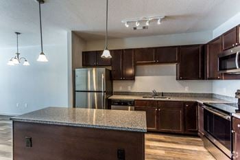 A kitchen with dark wood cabinets and granite countertops