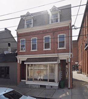 Lancaster apartment for rent - A red brick building with a white trim and a black car parked in front.