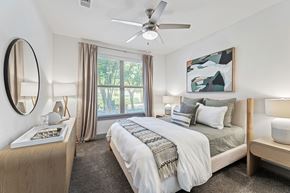 San Antonio apartment for rent - A bedroom with a large bed, a ceiling fan, and a painting on the wall.