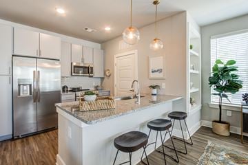 Summerville apartment for rent - A kitchen with a refrigerator, bar stools, and a potted plant.