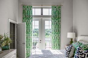 Savannah townhouse for rent - A bedroom with a bed, nightstand, and window with green curtains.