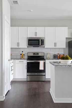 Mableton townhouse for rent - A kitchen with white cabinets and a marble countertop.