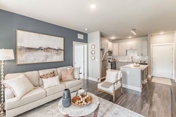 Madison apartment for rent - A modern living room with a white couch and a coffee table with a vase and a bowl of fruit on it.