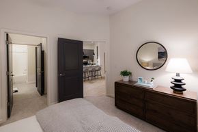 Wilmington apartment for rent - A bedroom with a bed, dresser, mirror, and lamp at Hudson at Renaissance Apartments, North Carolina 28405