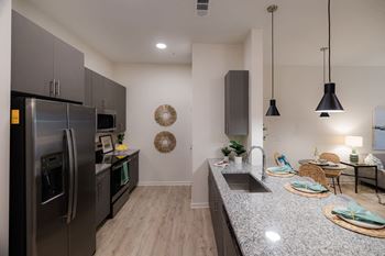 A modern kitchen with a stainless steel refrigerator and a dark grey countertop