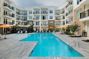 Wilmington apartment for rent - A large swimming pool in a residential building surrounded by lounge chairs and umbrellas at Hudson at Renaissance Apartments, North Carolina