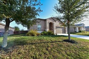 Anna apartment for rent - A house with a brown brick exterior and a white garage door is surrounded by trees and grass.