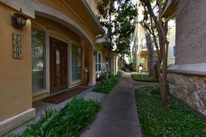 Dallas condo for rent - A narrow alley with a stone wall on one side and a row of houses on the other.
