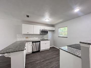 Dallas apartment for rent - A kitchen with white cabinets and a granite countertop.
