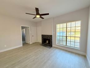 Dallas condo for rent - A room with a fireplace and a ceiling fan.