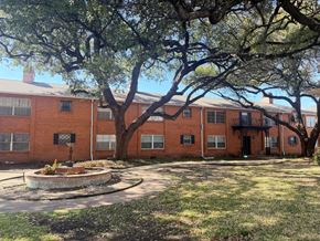 Dallas apartment for rent - A large tree in front of a red brick building.