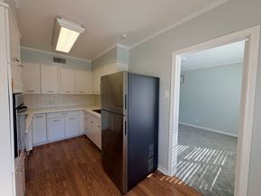 Dallas apartment for rent - A kitchen with a refrigerator and white cabinets.