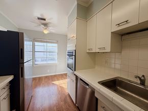 Dallas apartment for rent - A kitchen with white cabinets and a black refrigerator.