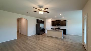 Anna apartment for rent - A spacious living room with a ceiling fan and a kitchen area in the background.