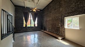 Dallas apartment for rent - A room with a brick wall and a ceiling fan.