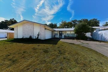 Richardson apartment for rent - A house with a white exterior and a grey roof is surrounded by a grassy area and a wooden fence.